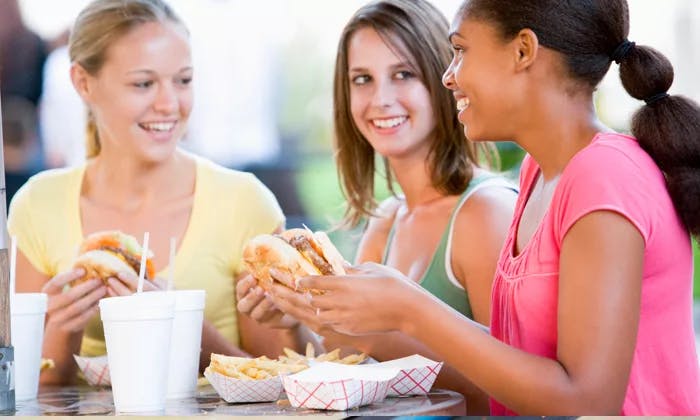 three women eating burgers